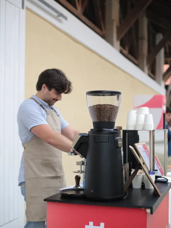 Gonçalo ao lado do moinho Compak, a trabalhar na máquina espresso durante o serviço.