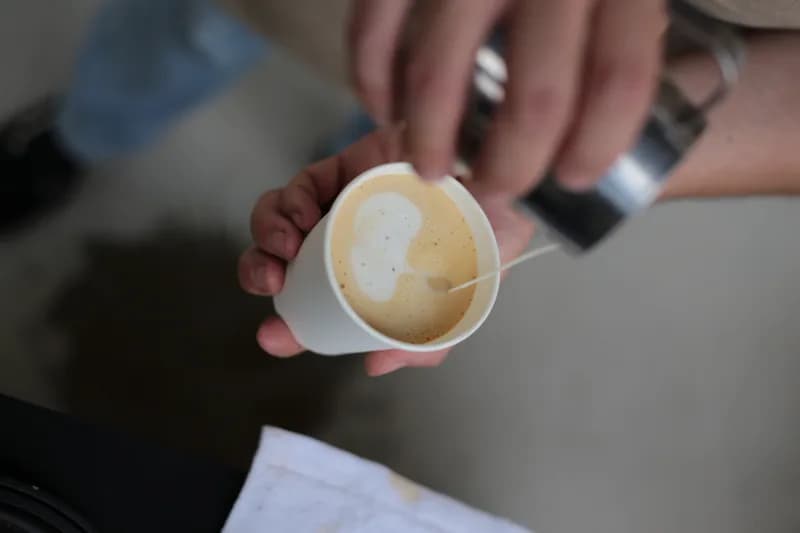 Latte art a ser finalizado num copo de cartão durante o serviço.